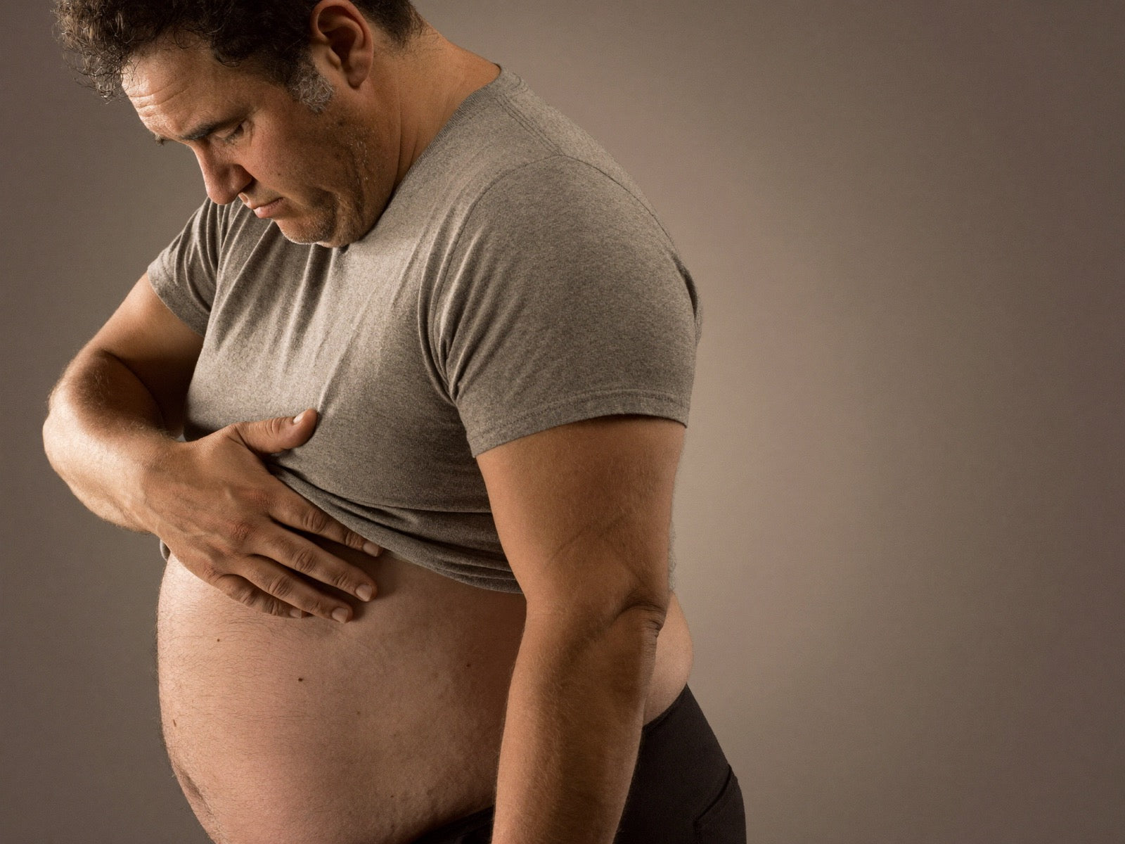 A man looking at his stubborn beer belly